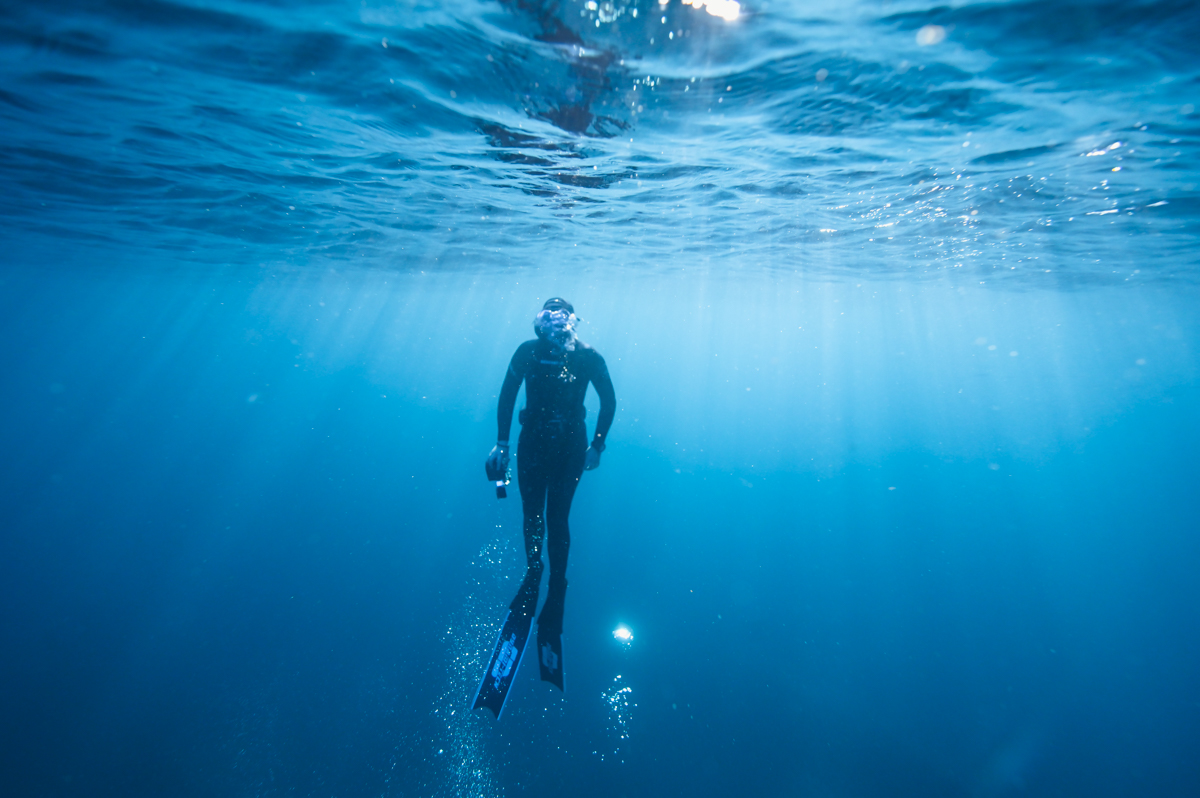 Freediver rising to the surface with ocean texture visible
